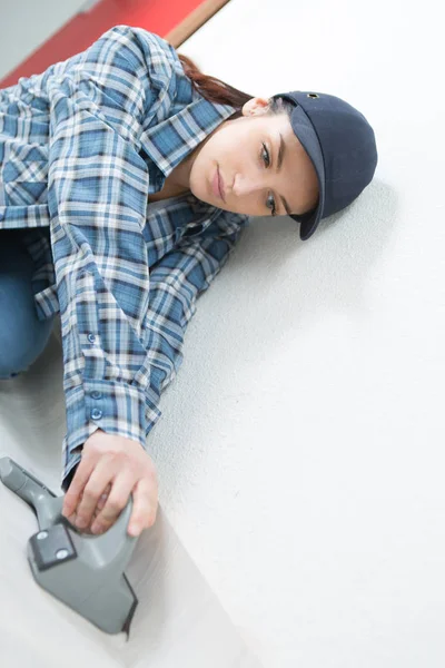 Vrouw kloppen onderlaag tegen muur met gereedschap — Stockfoto