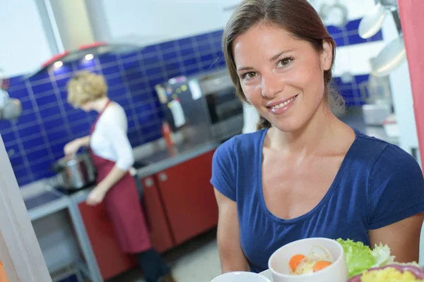 Porträt einer Dame, die Tablett mit Lebensmitteln in der Großküche hält — Stockfoto