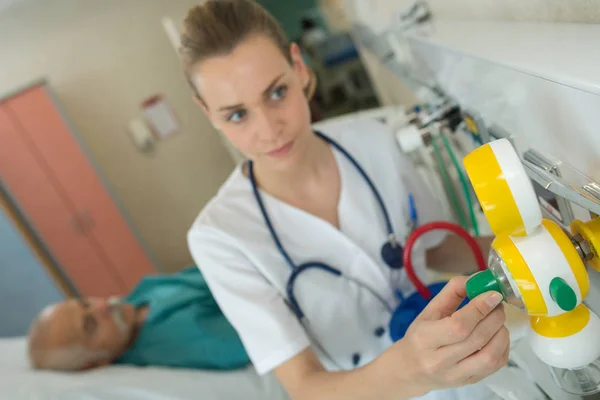 Sjuksköterska justera utrustning i patientens rum — Stockfoto