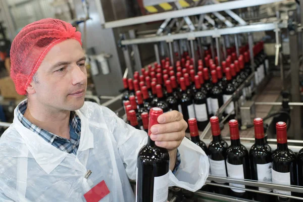 Trabajador inspeccionando botella de vino — Foto de Stock