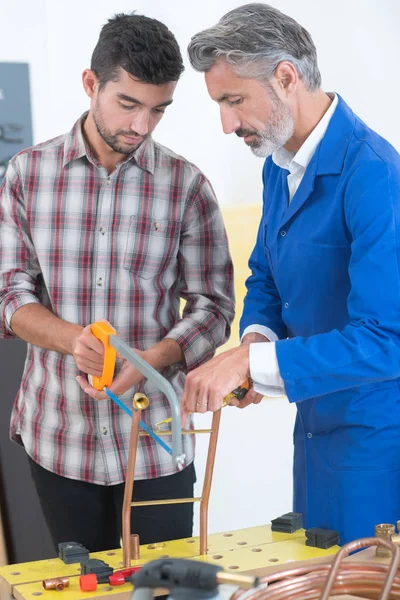 Aprendiz aprendiendo a cortar tubos de cobre —  Fotos de Stock