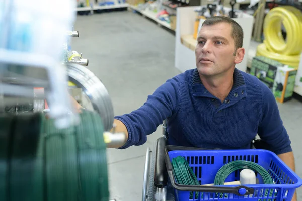Чоловік в інвалідному візку покупки в магазині обладнання — стокове фото