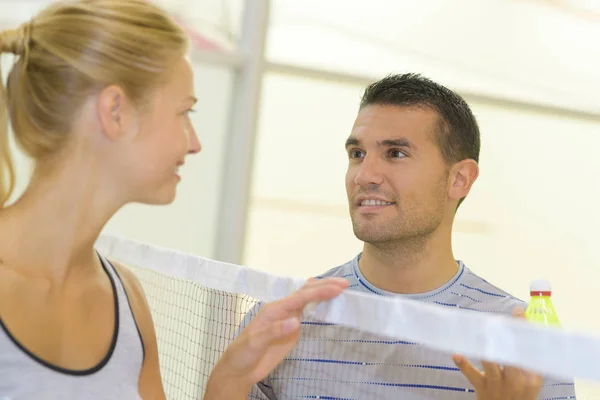 Man and woman looking at eachother over badminton net — Stock Photo, Image