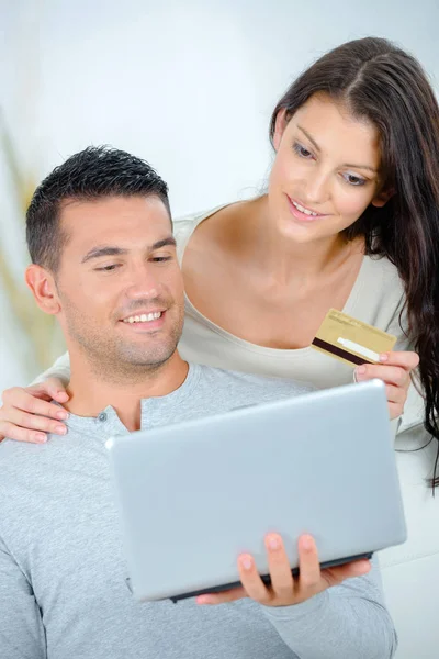 Пара смотрит на ноутбук и держит кредитную карту — стоковое фото