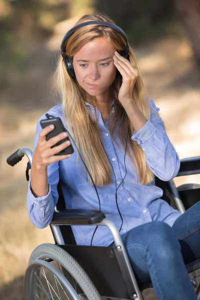 Lady in wheelchair puzzling over cellphone — Stock Photo, Image
