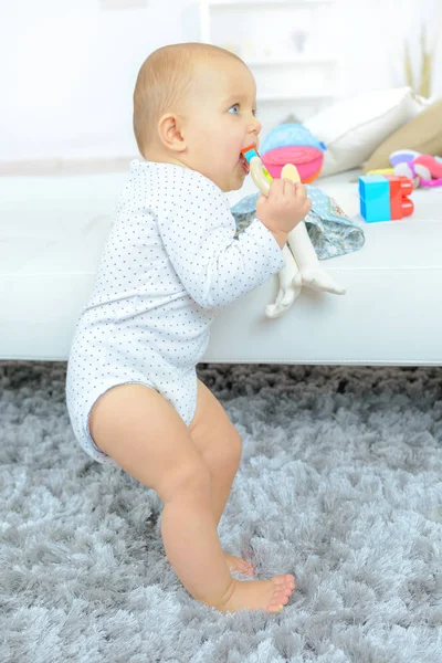 Bambino in piedi con divano e giocattoli — Foto Stock