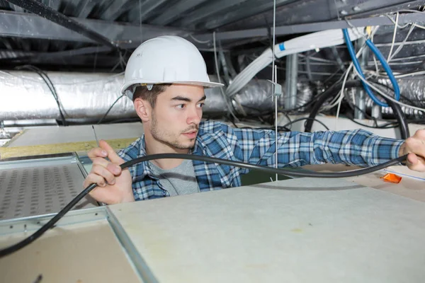 Eletricista trabalhando no espaço do telhado — Fotografia de Stock
