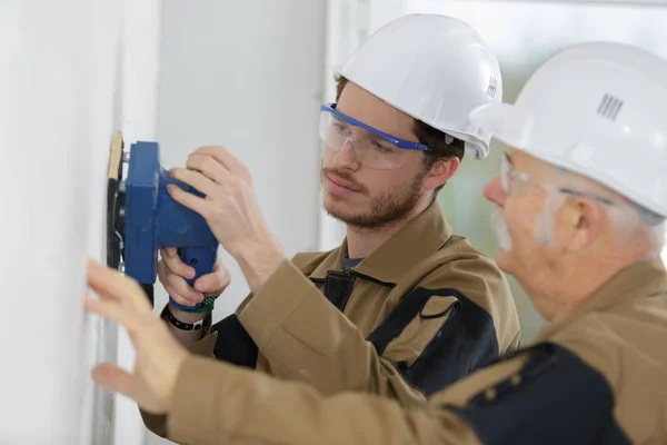 Lärling tradesman lära sig använda sander — Stockfoto