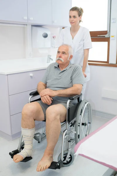 Медсестра толкает пожилого человека в инвалидном кресле — стоковое фото