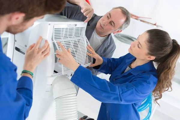 Praktikanter som arbetar på en luftkonditionering enhet — Stockfoto