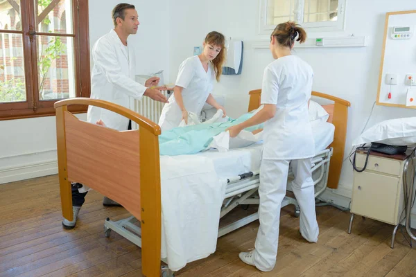 Nurses lifting patient under doctor s supervision — Stock Photo, Image