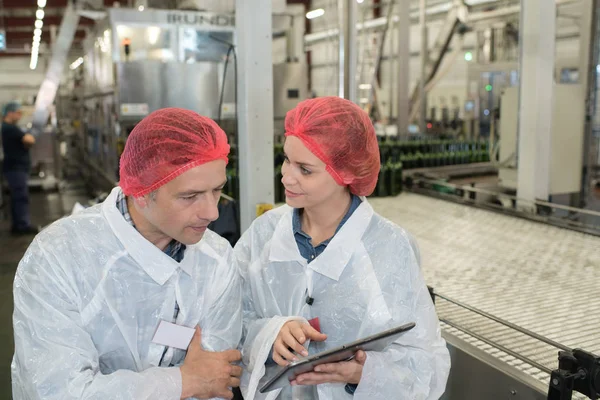 Homem e mulher na fábrica olhando para tela tablet — Fotografia de Stock