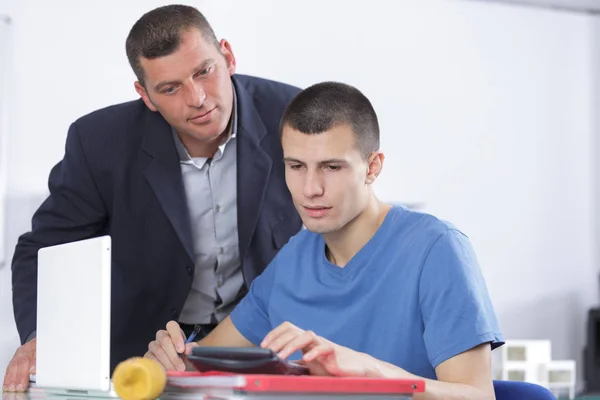 Літній чоловік допомагає молодшому чоловікові на комп'ютері — стокове фото
