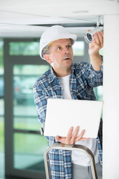 Auftragnehmer mit Laptop und Überwachungskamera — Stockfoto