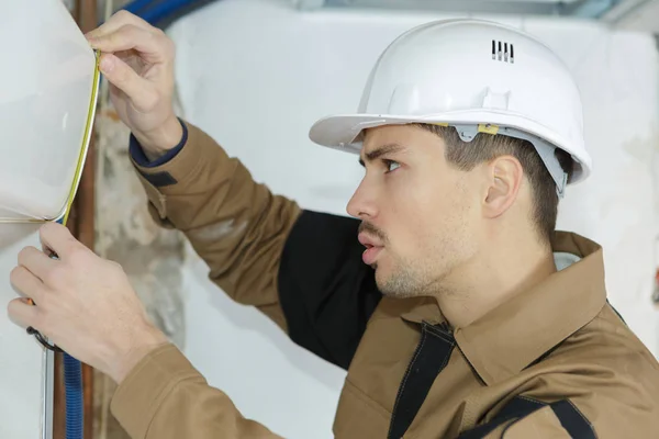 Joven trabajador de la construcción medición de pared —  Fotos de Stock