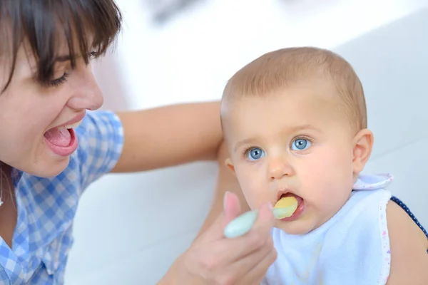 Mother spoon feeding baby — Stock Photo, Image