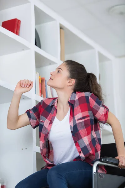 需要从高架子上的东西的坐轮椅的女孩 — 图库照片