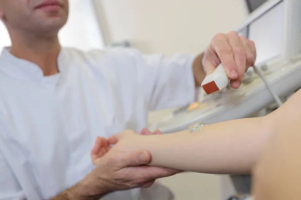 Doctor performing ultrasound on arm — Stock Photo, Image