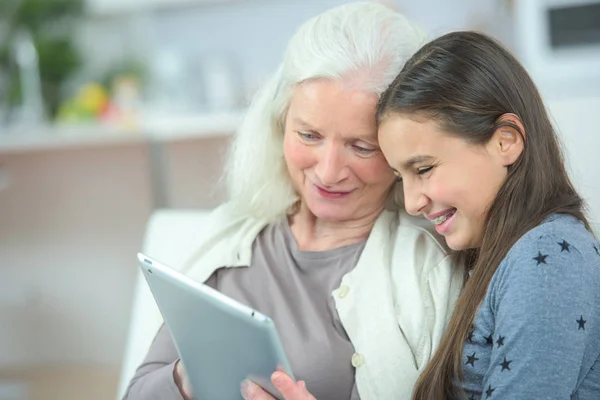 Torun ve büyükanne tablet vasıl bakarken gülüyor — Stok fotoğraf