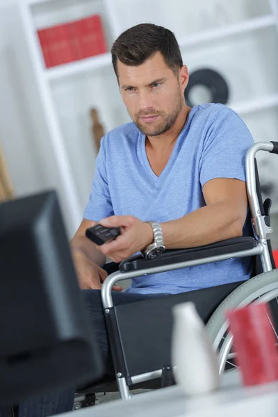 Schöner behinderter Mann, der im Wohnzimmer fernsieht — Stockfoto