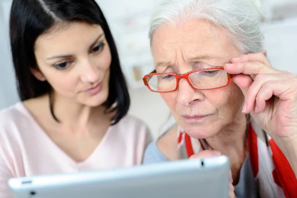 Damen som hjälper äldre kvinna användning dator — Stockfoto