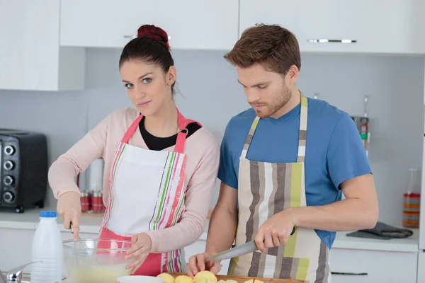Jeune couple cuisine la nourriture dans une cuisine — Photo