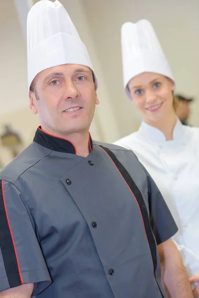 Retrato de confiante chef feminino e masculino na cozinha — Fotografia de Stock