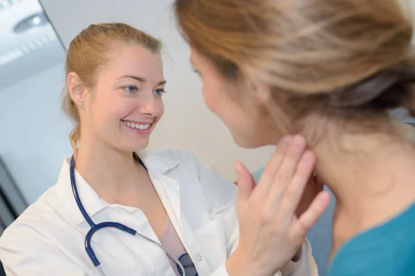 Жінка-лікар перевіряє жіночий горло — стокове фото