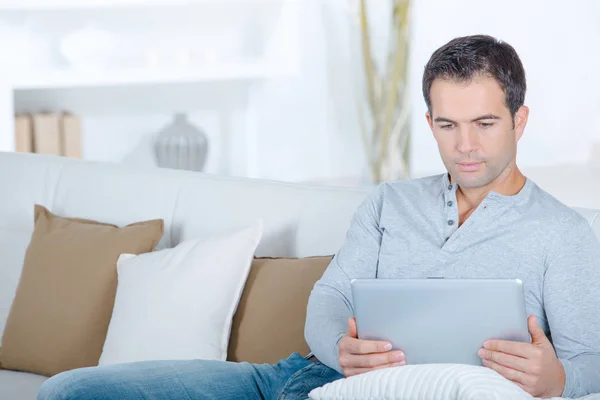 Hombre en el sofá usando la tableta — Foto de Stock