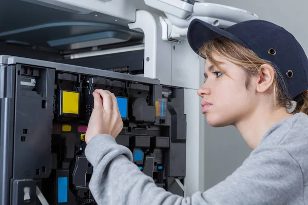 Jovem técnico feminino corrigir a impressora — Fotografia de Stock