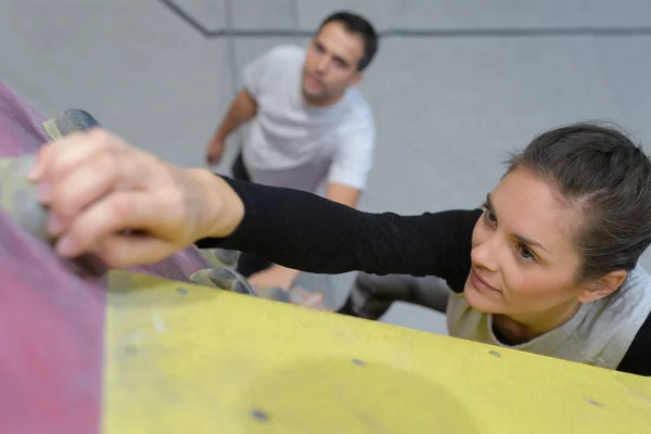 Mujer alcanzando agarre en pared de escalada —  Fotos de Stock