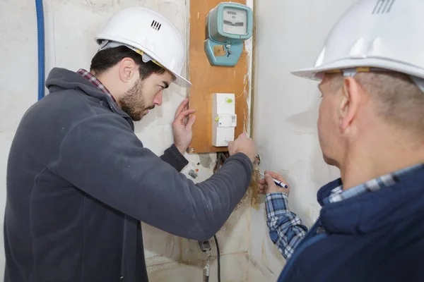 builders checking electrical panel indoors