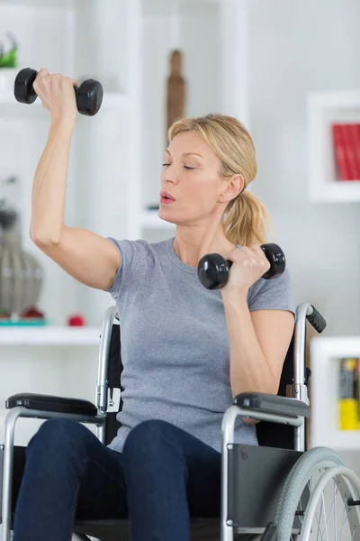 Kvinna på en rullstol gör sjukgymnastik hemma — Stockfoto