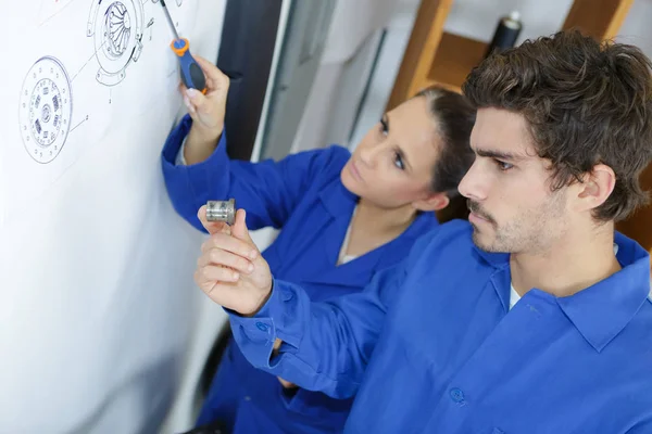 Technicians identifying part on exploded technical drawing — Stock Photo, Image