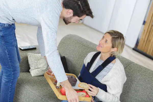 Mannen serveringsbricka av mat till skadade dam — Stockfoto