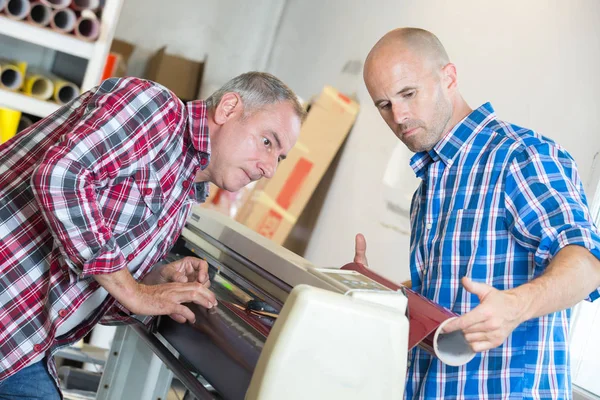 Lavoratori che controllano un funzionamento a getto d'inchiostro formato stampante — Foto Stock