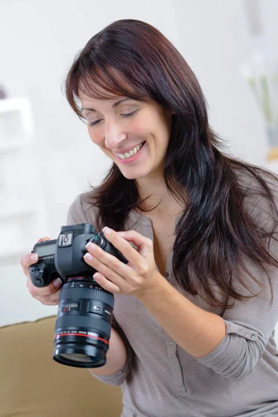 Fotógrafa mujer feliz toma imágenes con la cámara dslr —  Fotos de Stock
