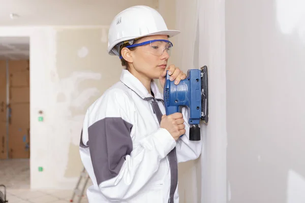 Female construction worker smoothing wall surface — Stock Photo, Image