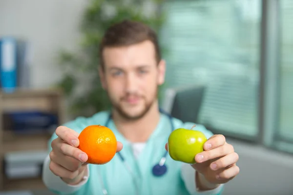 Arzt zeigt eine Birne und einen Apfel — Stockfoto