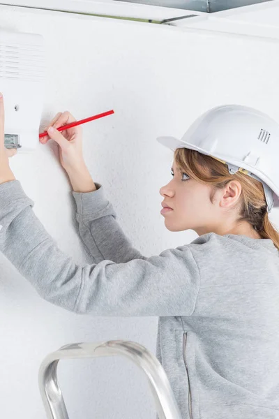 Woman marking position to fit alarm on wall — Stock Photo, Image