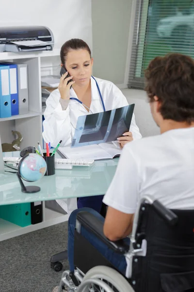 Medico guardando i raggi X, paziente in sedia a rotelle — Foto Stock