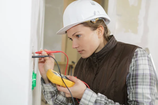 Elektrikerin kalibriert eine Haushaltssteckdose — Stockfoto