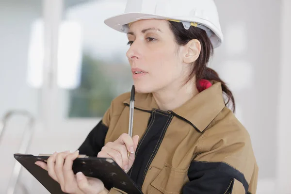 Mujer trabajadora pensando mientras mira portapapeles —  Fotos de Stock