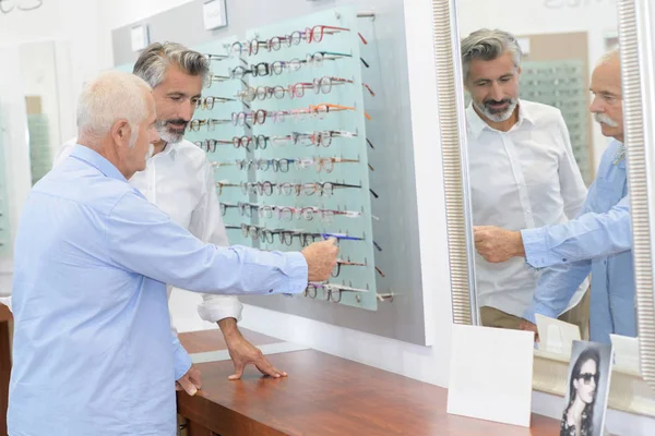 Testes seniores novos óculos com óptico — Fotografia de Stock
