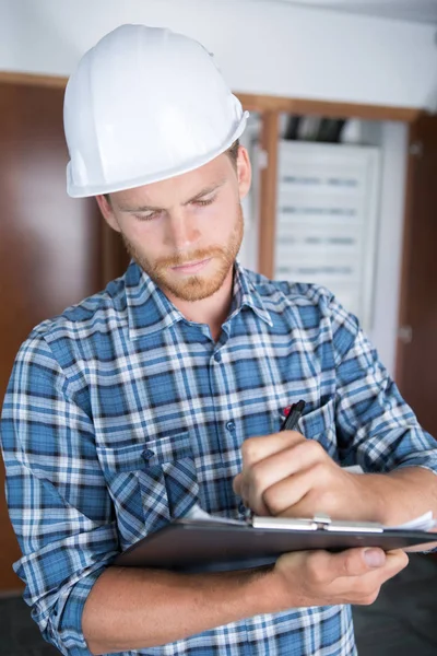 Uomo in hardhat scrittura sugli appunti — Foto Stock