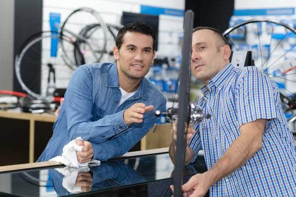 Hombre comprueba una bicicleta antes de comprar en la tienda de deportes — Foto de Stock