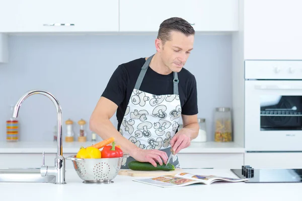 Homem cortando pepinos em uma cozinha — Fotografia de Stock