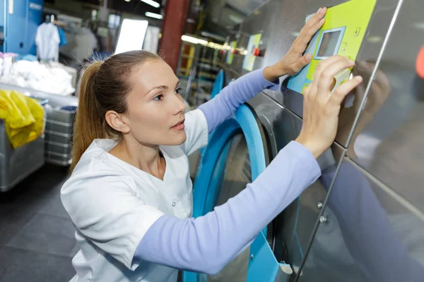 Arbetaren laster tvätt kläder i tvättmaskinen — Stockfoto