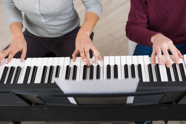 Четыре руки играют на пианино — стоковое фото