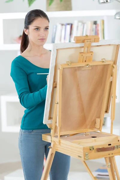 Молодая женщина с мольбертом рисует картину — стоковое фото